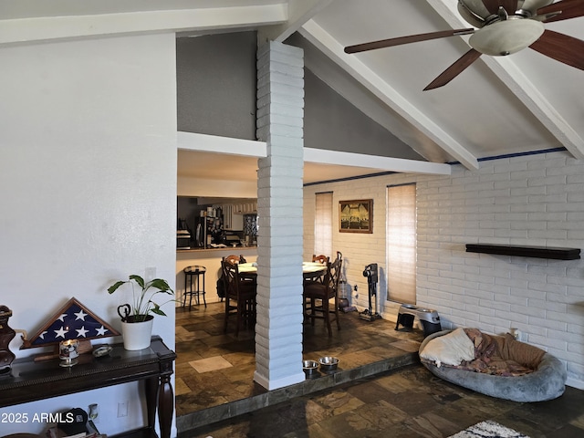 interior space with brick wall, ceiling fan, beamed ceiling, stone tile flooring, and ornate columns