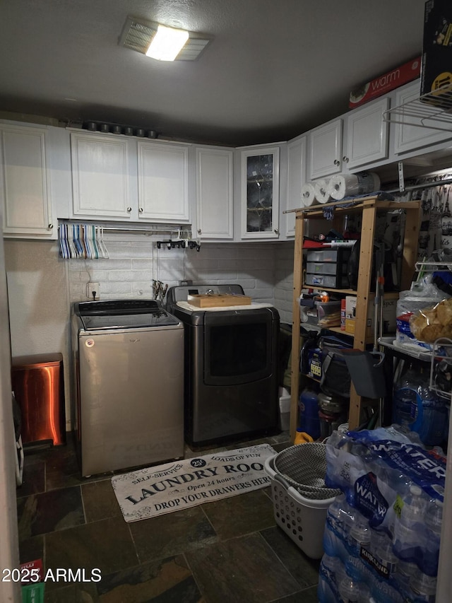 clothes washing area with stone finish flooring, cabinet space, and washing machine and clothes dryer