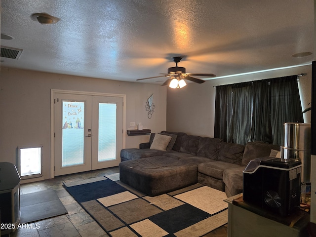 living area with visible vents, a textured ceiling, stone tile flooring, french doors, and ceiling fan