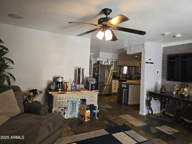 living room featuring a textured ceiling, ceiling fan, and dark floors