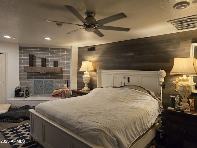 bedroom featuring recessed lighting, visible vents, wood walls, and a textured ceiling