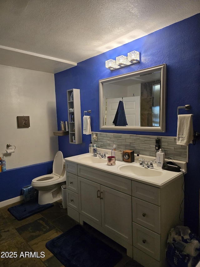 bathroom featuring double vanity, decorative backsplash, a textured ceiling, and a sink