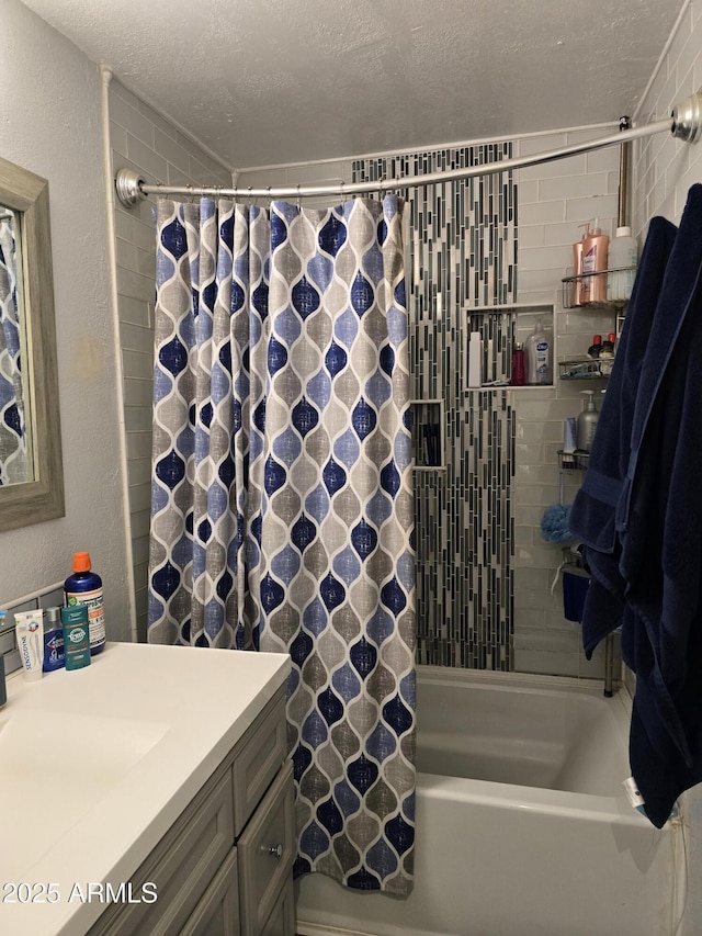 bathroom with shower / bath combo with shower curtain, a textured ceiling, vanity, and a textured wall