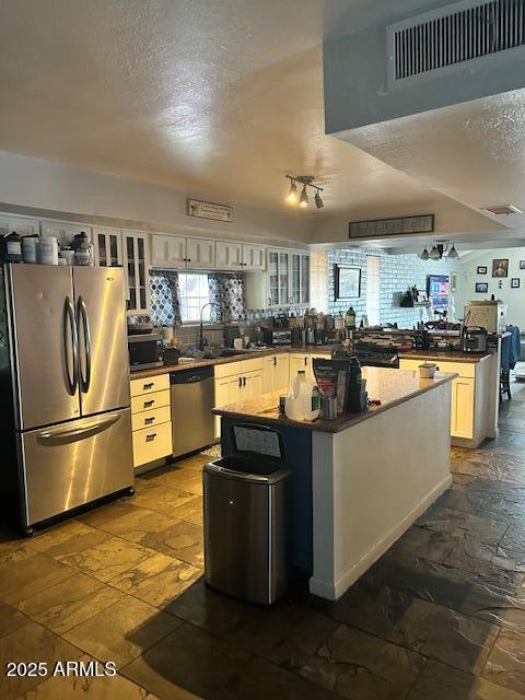 kitchen featuring decorative backsplash, dark countertops, stone tile flooring, and stainless steel appliances
