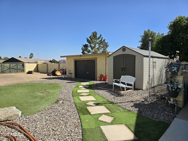 view of yard featuring fence, a garage, an outdoor structure, a storage unit, and a patio