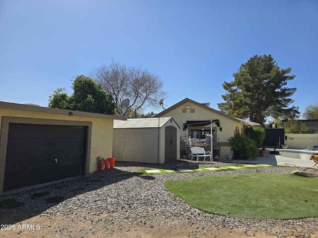 exterior space with stucco siding, an outbuilding, a storage shed, a garage, and a patio area