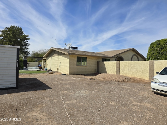 view of property exterior featuring brick siding and fence