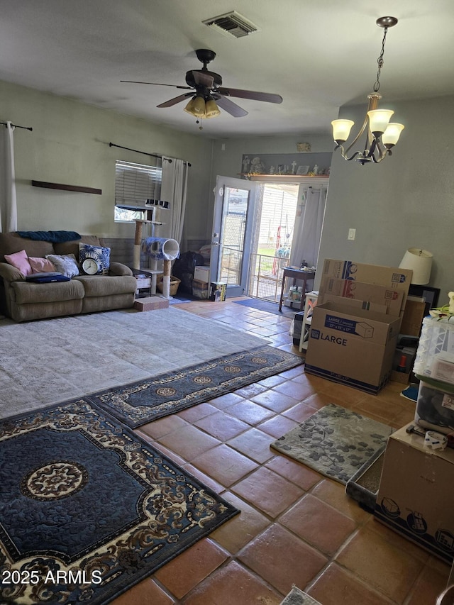 living area featuring tile patterned floors, visible vents, and ceiling fan with notable chandelier