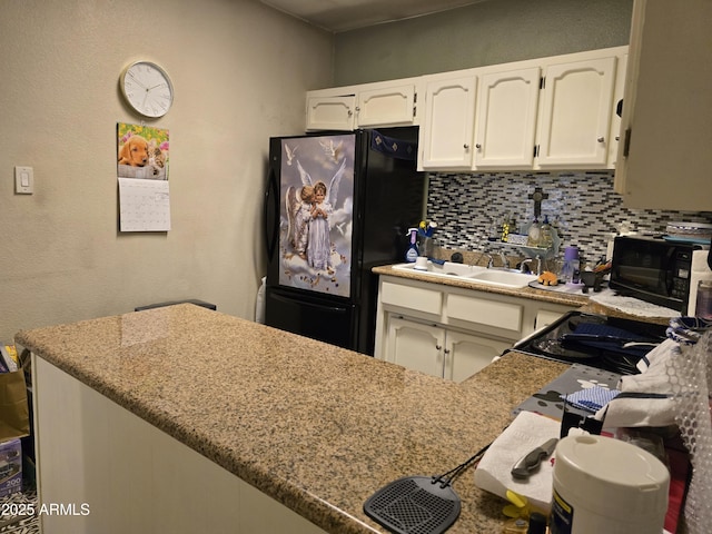 kitchen featuring decorative backsplash, white cabinetry, black appliances, and light stone countertops