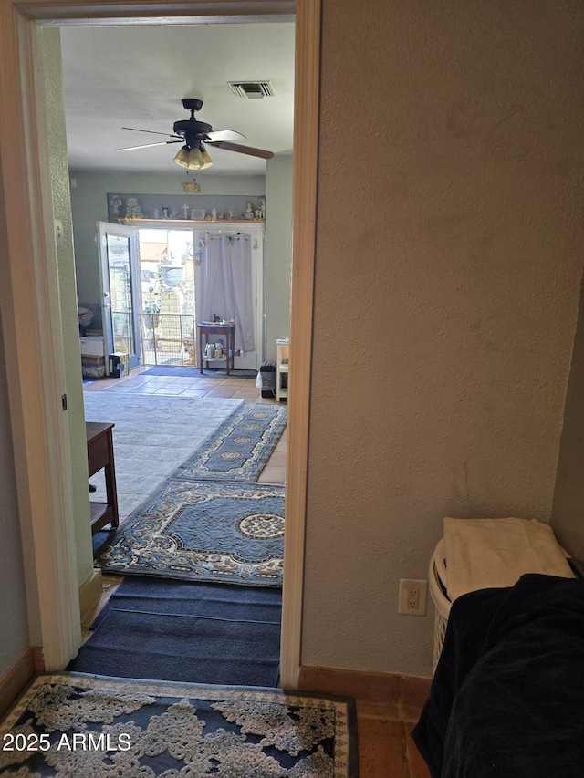 corridor with visible vents, baseboards, and a textured wall