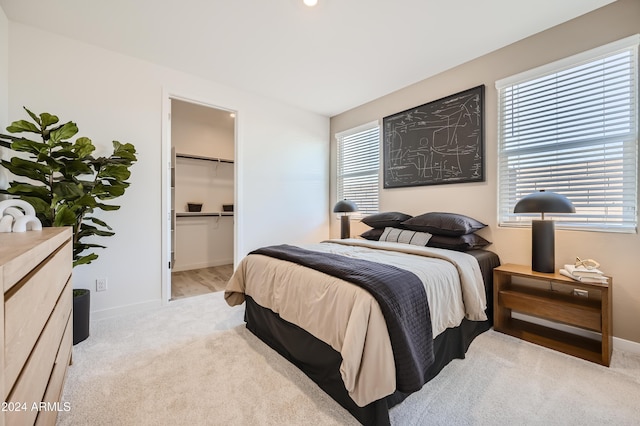 bedroom with a walk in closet and light carpet