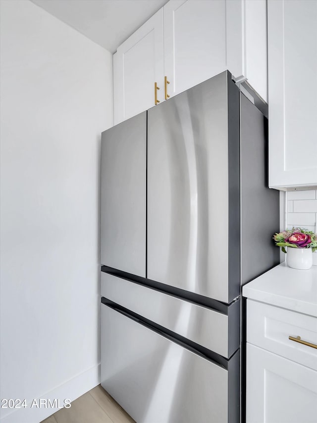 details with white cabinetry, tasteful backsplash, and stainless steel refrigerator