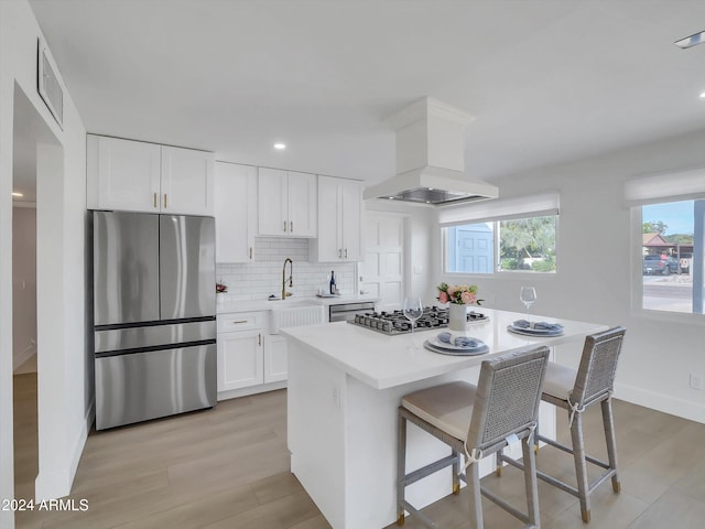 kitchen with a kitchen breakfast bar, white cabinetry, custom range hood, and stainless steel appliances