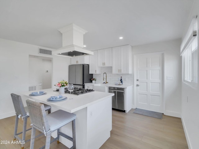 kitchen featuring premium range hood, appliances with stainless steel finishes, white cabinets, and light hardwood / wood-style floors