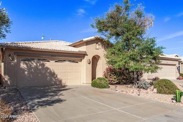 view of front of house with a garage, driveway, a tile roof, and stucco siding