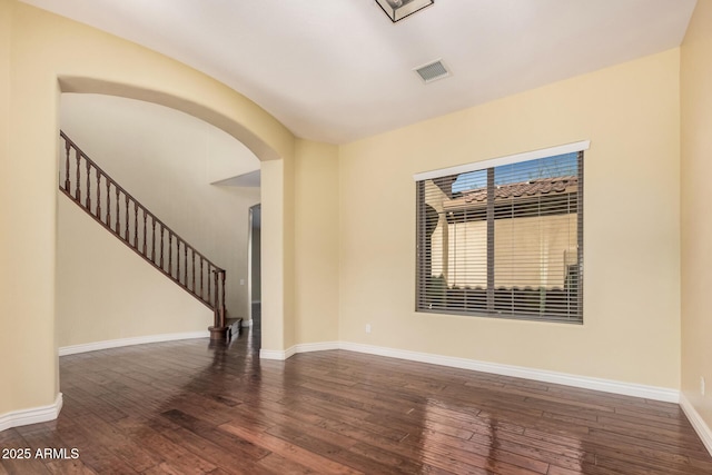 26796 N 86th Ln, Peoria, AZ 85383 - empty room with visible vents, baseboards, stairway, arched walkways, and hardwood / wood-style floors