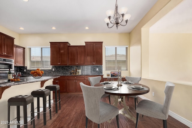 26796 N 86th Ln, Peoria, AZ 85383 - kitchen with backsplash, a kitchen bar, dark wood finished floors, baseboards, and an inviting chandelier