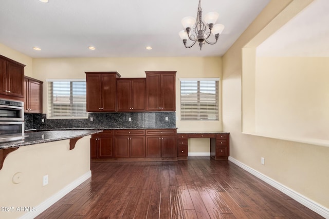 26796 N 86th Ln, Peoria, AZ 85383 - kitchen with double oven, a breakfast bar, backsplash, and dark wood-style flooring