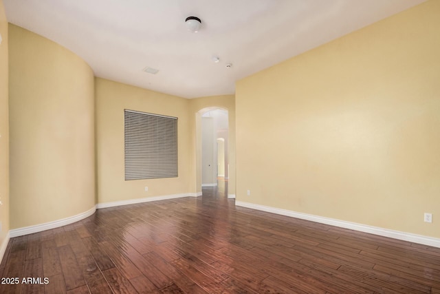26796 N 86th Ln, Peoria, AZ 85383 - empty room featuring arched walkways, baseboards, and dark wood-type flooring