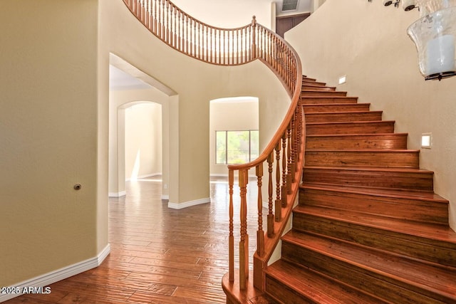 26796 N 86th Ln, Peoria, AZ 85383 - staircase with arched walkways, baseboards, a high ceiling, and wood-type flooring