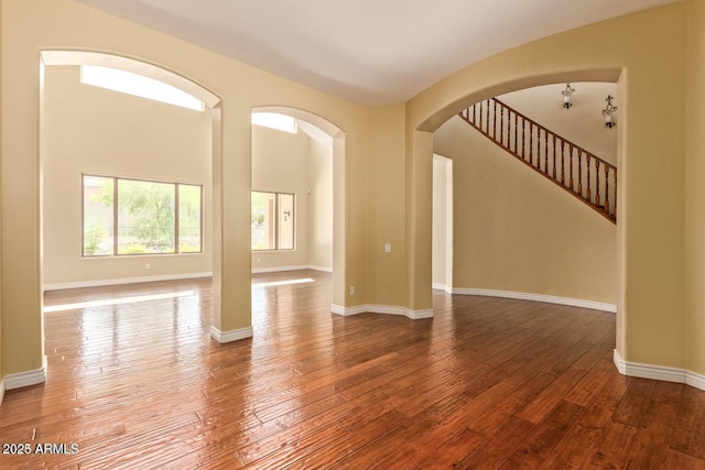 26796 N 86th Ln, Peoria, AZ 85383 - unfurnished room featuring baseboards, stairs, arched walkways, and wood-type flooring