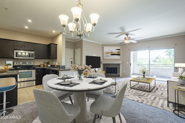 5345 E Van Buren St Unit 305, Phoenix, AZ 85008 - dining area featuring a ceiling fan, a tile fireplace, a chandelier, crown molding, and light colored carpet