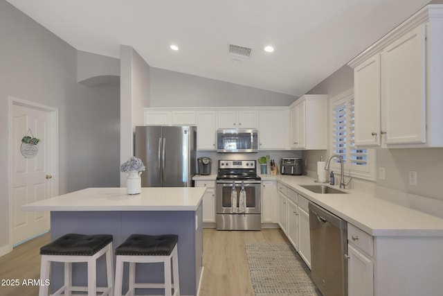 kitchen with a breakfast bar, sink, a center island, appliances with stainless steel finishes, and white cabinets