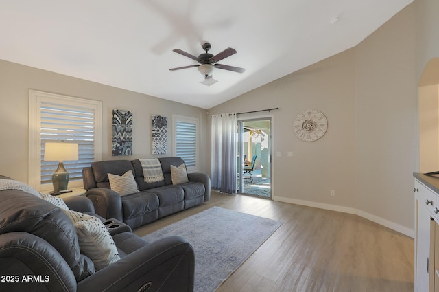 living room with ceiling fan, vaulted ceiling, and light hardwood / wood-style flooring