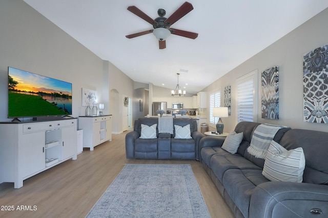 living room featuring vaulted ceiling, ceiling fan with notable chandelier, and light hardwood / wood-style floors