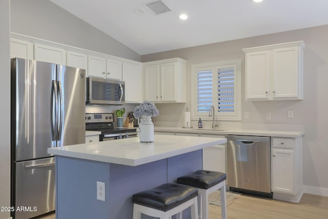 kitchen featuring sink, a breakfast bar area, stainless steel appliances, a center island, and white cabinets