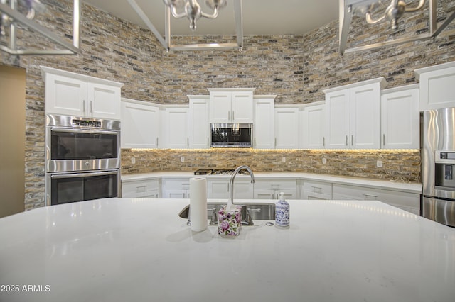 710 W Ardmore Rd, Phoenix, AZ 85041 - kitchen with appliances with stainless steel finishes, a sink, light countertops, decorative backsplash, and white cabinets