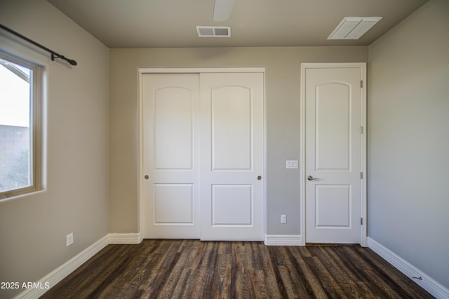 710 W Ardmore Rd, Phoenix, AZ 85041 - unfurnished bedroom featuring dark wood-style floors, a closet, baseboards, and multiple windows