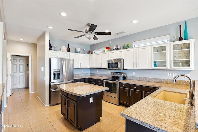 kitchen with light stone countertops, ceiling fan, appliances with stainless steel finishes, dark brown cabinetry, and sink