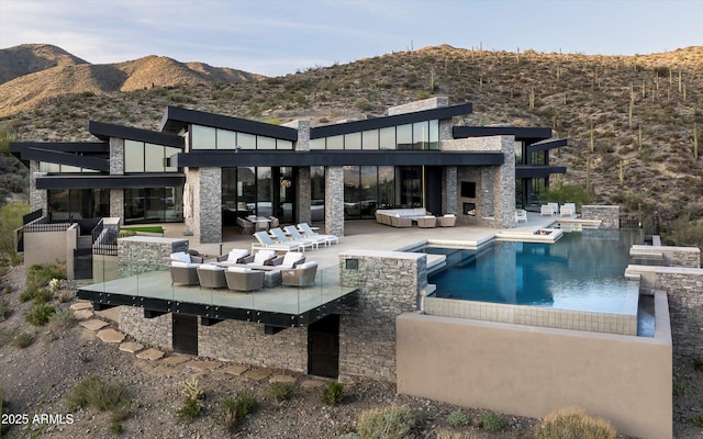 9643 E Cintarosa Pass, Scottsdale, AZ 85262 - back of house with a mountain view, a patio area, a pool with connected hot tub, stone siding, and an outdoor hangout area