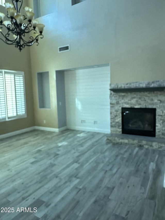 13259 W Flower St, Litchfield Park, AZ 85340 - unfurnished living room with wood finished floors, a chandelier, baseboards, visible vents, and a high ceiling