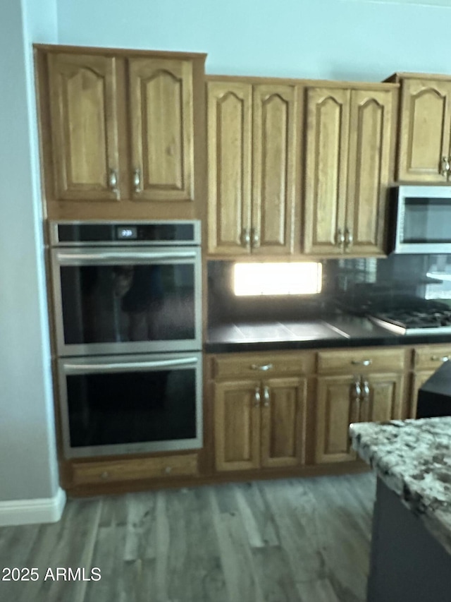 13259 W Flower St, Litchfield Park, AZ 85340 - kitchen with baseboards, light wood-type flooring, stainless steel appliances, and backsplash