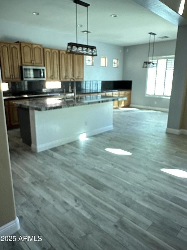 13259 W Flower St, Litchfield Park, AZ 85340 - kitchen featuring stainless steel microwave, a sink, baseboards, wood finished floors, and a center island with sink