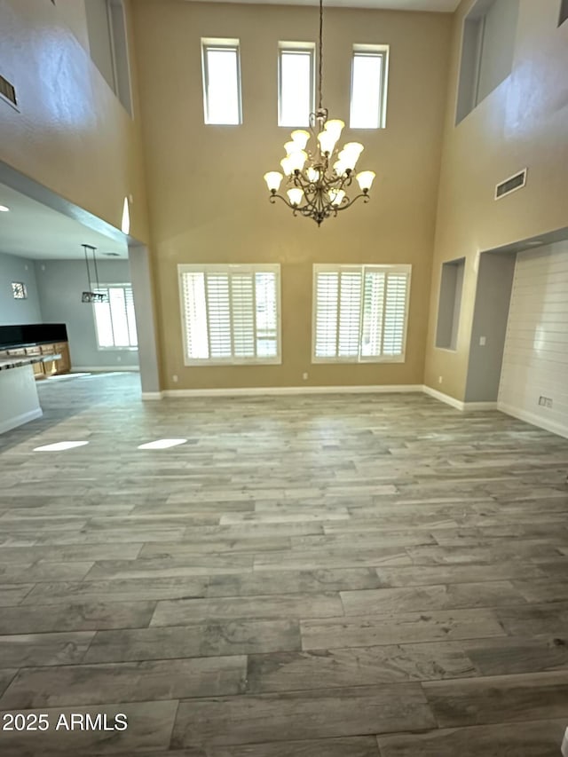 13259 W Flower St, Litchfield Park, AZ 85340 - unfurnished living room with a notable chandelier, visible vents, baseboards, a towering ceiling, and wood finished floors