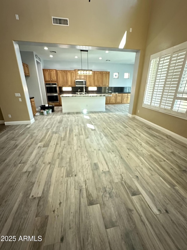 13259 W Flower St, Litchfield Park, AZ 85340 - unfurnished living room with visible vents, light wood-style floors, baseboards, recessed lighting, and a towering ceiling