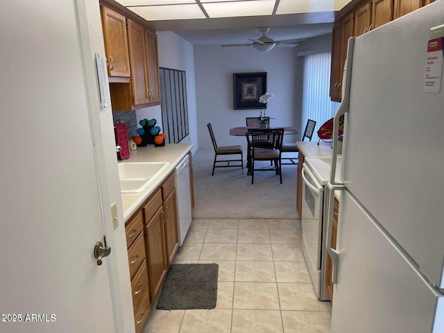 kitchen with brown cabinetry, white appliances, light countertops, and light tile patterned floors