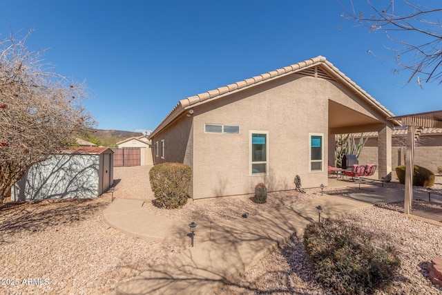 view of property exterior with a storage unit and a patio area