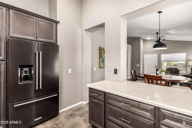 kitchen with lofted ceiling, high quality fridge, hanging light fixtures, dark brown cabinets, and light stone countertops