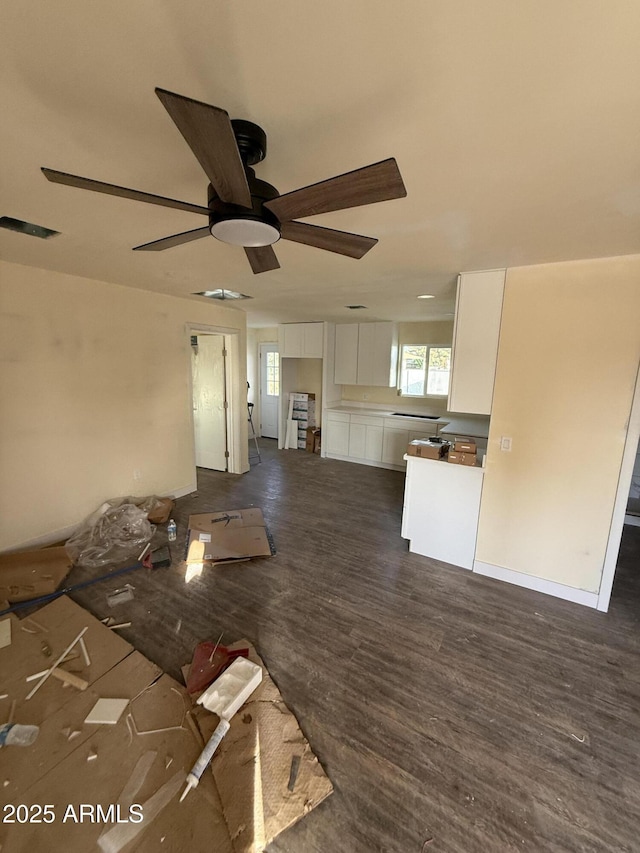 unfurnished living room featuring dark wood-type flooring and ceiling fan