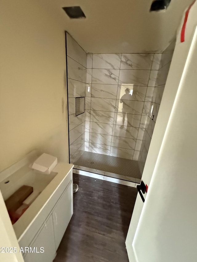 bathroom featuring vanity, hardwood / wood-style floors, and tiled shower