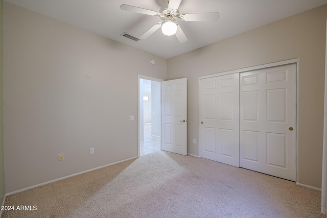 unfurnished bedroom featuring ceiling fan, a closet, and light colored carpet