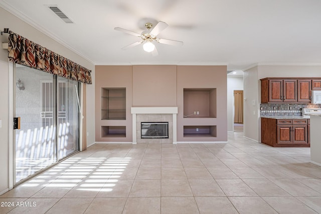 unfurnished living room with built in features, ceiling fan, ornamental molding, and light tile patterned flooring