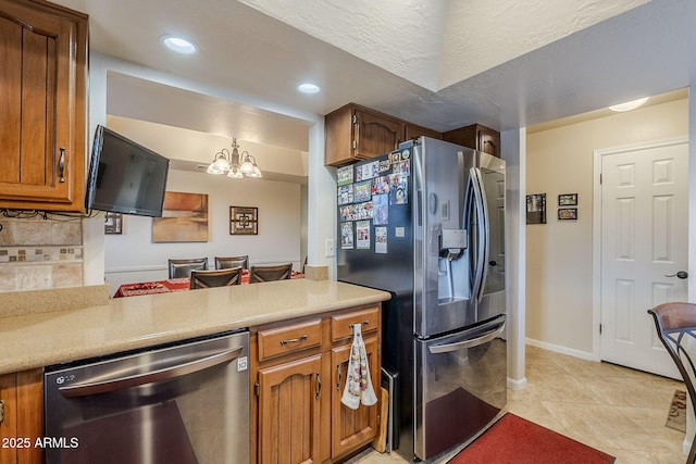 kitchen featuring appliances with stainless steel finishes, tasteful backsplash, a textured ceiling, light tile patterned flooring, and decorative light fixtures