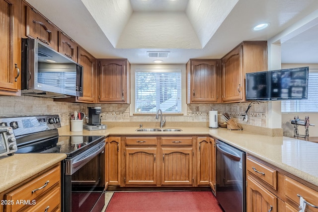 kitchen featuring sink, a textured ceiling, appliances with stainless steel finishes, a tray ceiling, and decorative backsplash