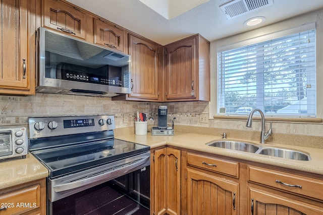 kitchen with appliances with stainless steel finishes, sink, and decorative backsplash