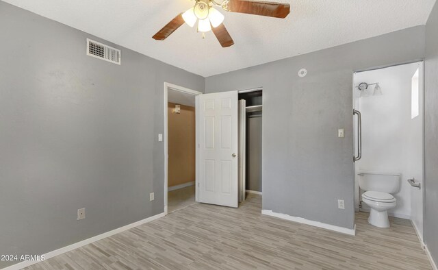 unfurnished bedroom with a closet, a textured ceiling, ceiling fan, ensuite bathroom, and light hardwood / wood-style flooring